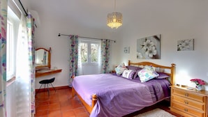 Un dormitorio con cama, cómoda de madera y ventana con cortinas.