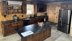 A kitchen with wooden cabinets, a central island, a refrigerator, and a built-in oven. - Rustic Barndominium Retreat (Pleasanton)