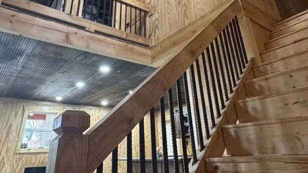 A multi-level wooden interior with a staircase and a decorative ceiling light. - Rustic Barndominium Retreat (Pleasanton)