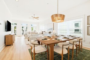Un amplio salón con una mesa de comedor para seis personas, un sofá y un televisor montado en la pared.