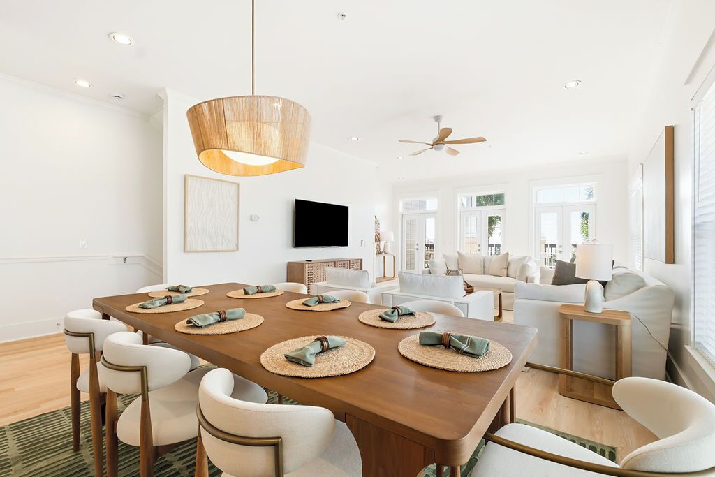 Un espace repas moderne avec une table en bois dressée pour six personnes, entourée de chaises blanches.