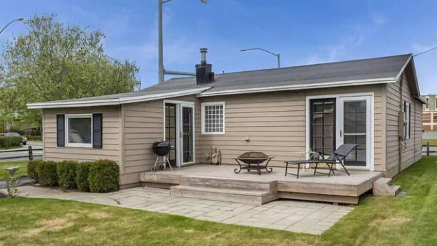 Ein Bungalow mit überdachter Terrasse, Grill und Gartenmöbeln.