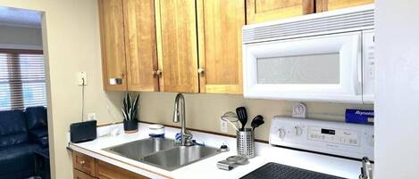 Eine Küche mit Holzausstattung, einem Doppelwaschbecken, einer Mikrowelle, einem Herd und einem Toaster.