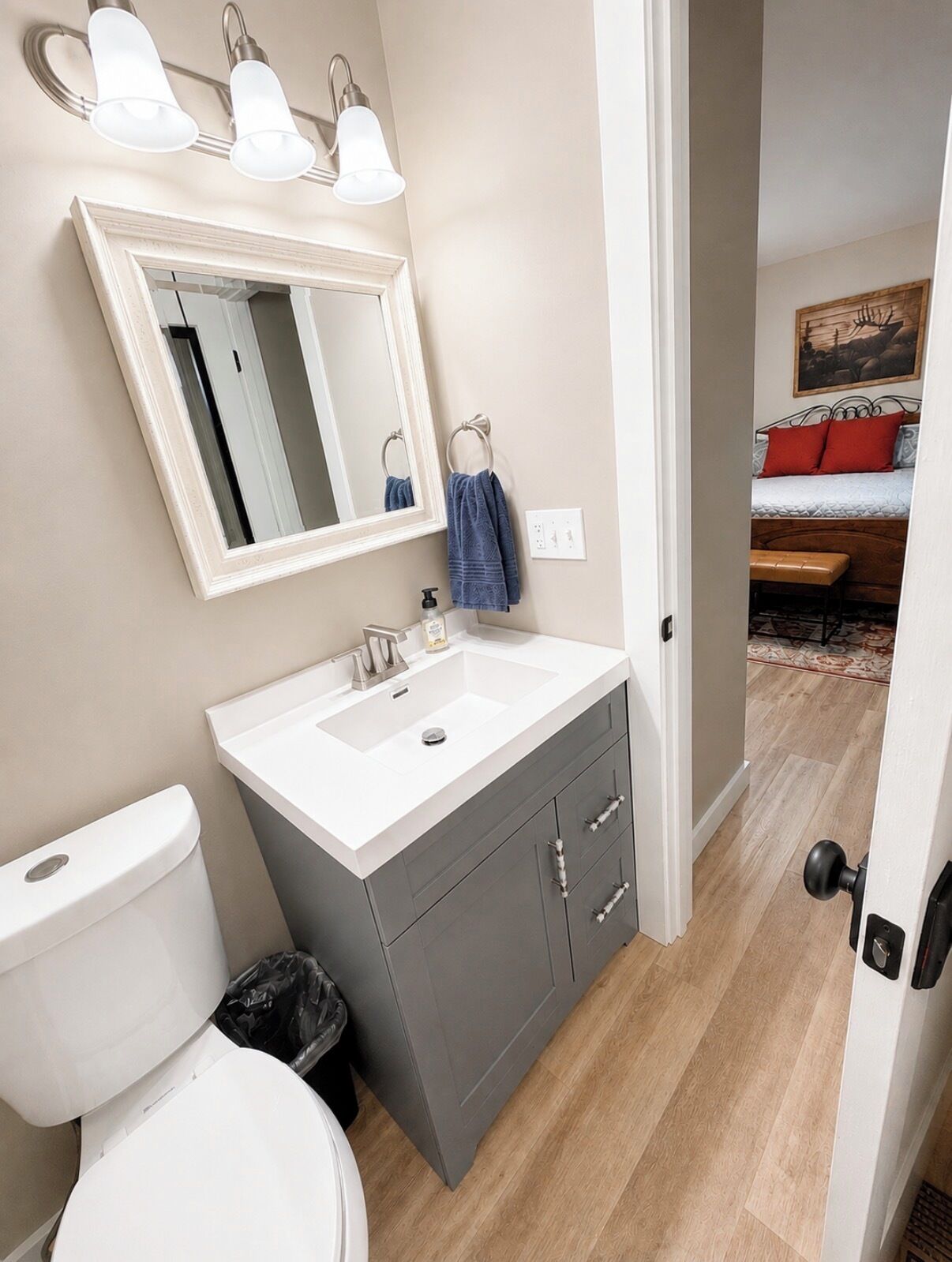 Une salle de bain comprenant des toilettes, un lavabo, un meuble-lavabo et un miroir.