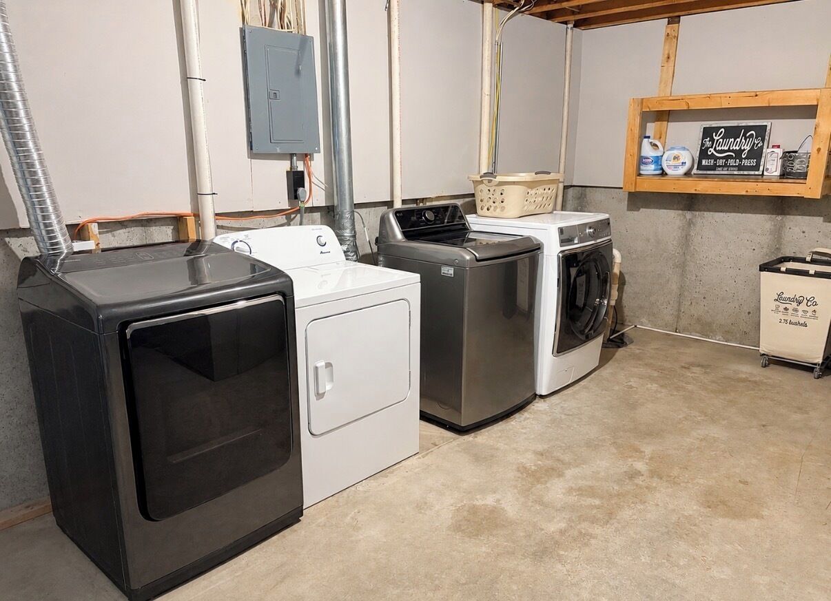 A laundry room with a washer, dryer, and stacked laundry baskets.