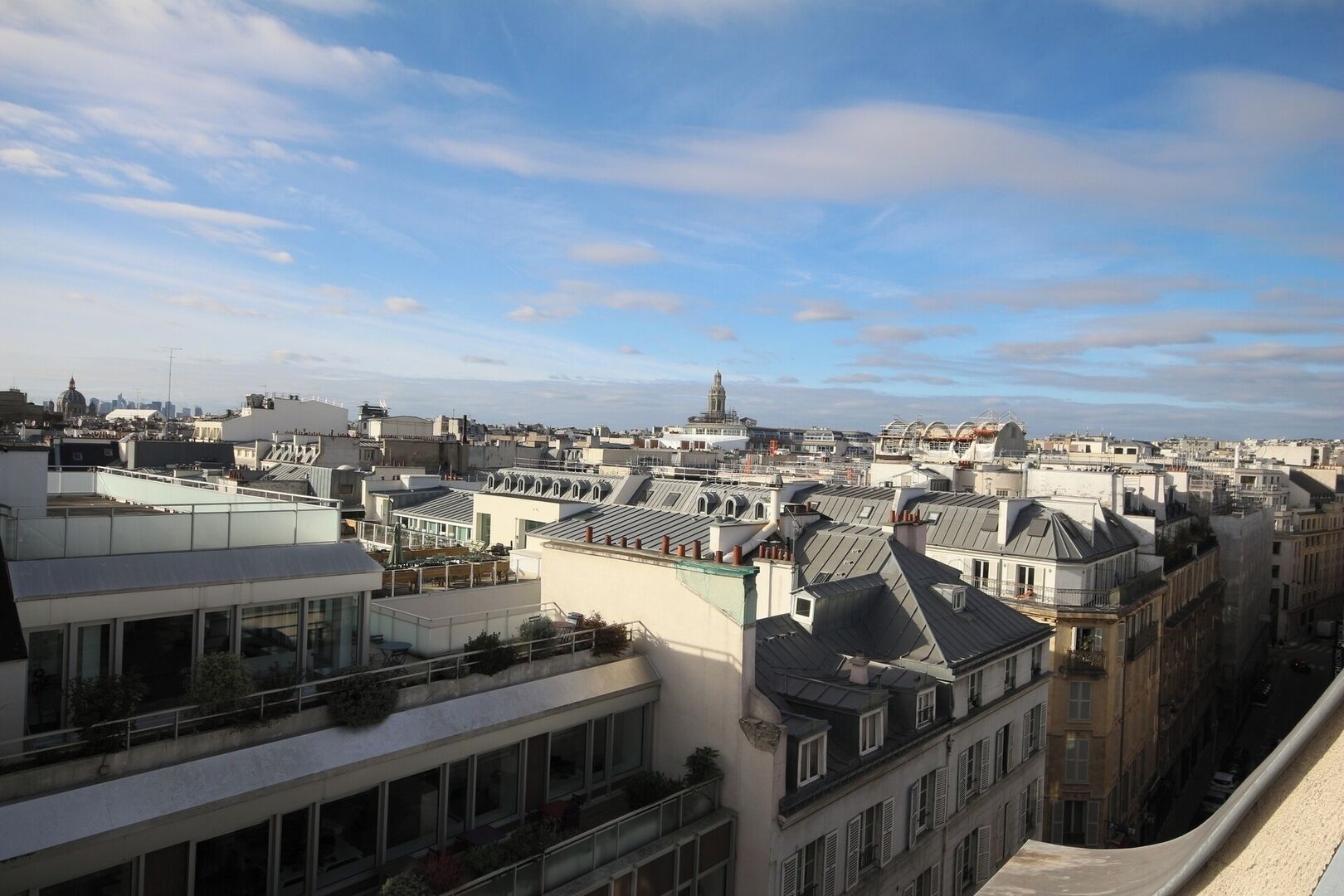 Une vue urbaine avec de nombreux bâtiments, dont une imposante structure en forme de dôme qui se distingue au loin.