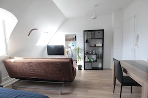 Ein moderner, gut beleuchteter Raum mit einem Bett, einem Schreibtisch und einem Fernseher.