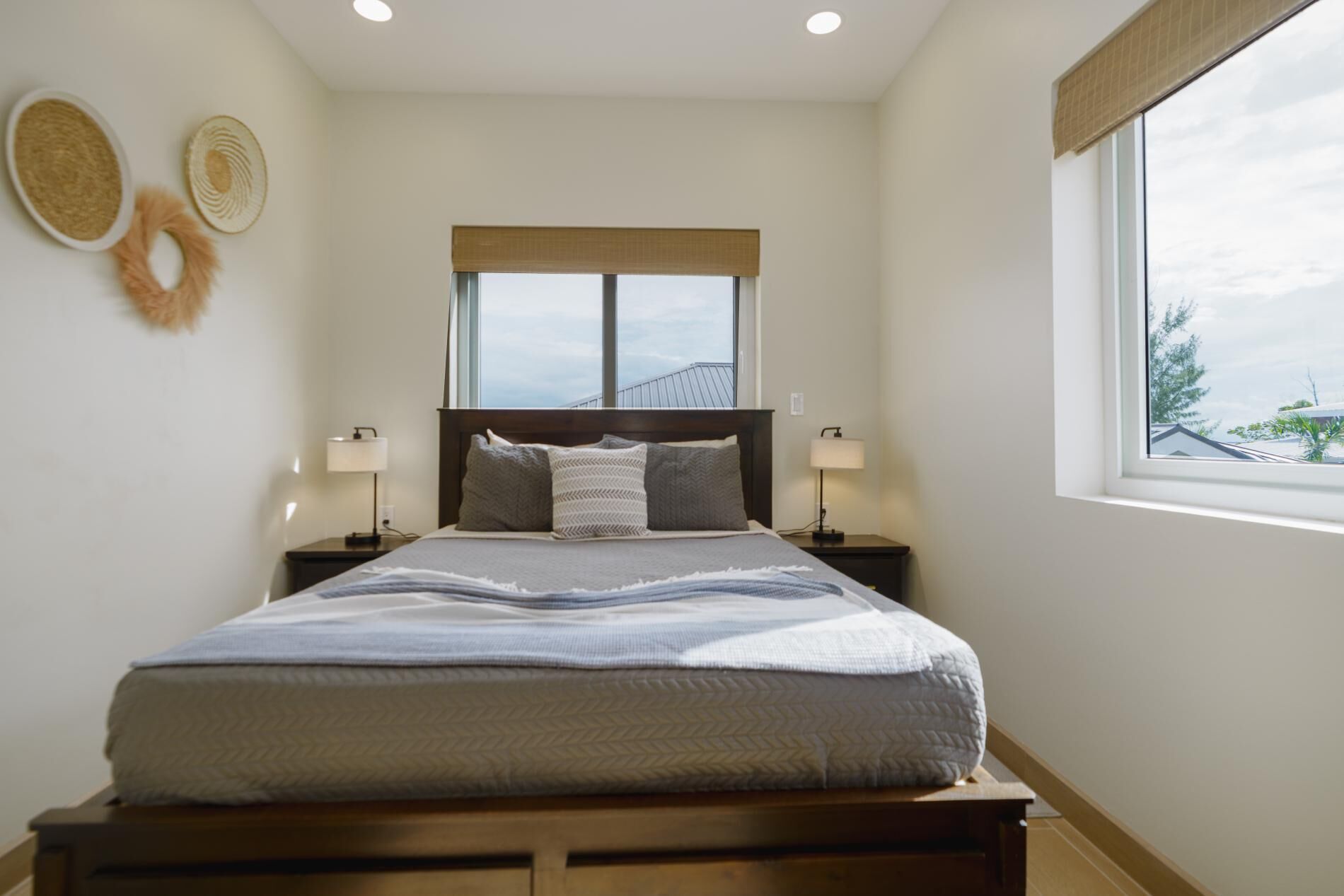 Quarto bem arrumado com cama, duas mesas de cabeceira, uma janela com vista e detalhes na parede.