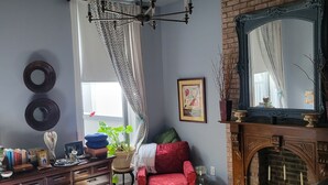 Una stanza con un letto, una poltrona rossa, un camino, uno specchio e un lampadario.