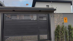 A modern building with a large black garage door, a small window, and a number '38' sign on the wall. - Refuge 3 Indaiá Beach Bertioga 150 meters from the sea (Bertioga)