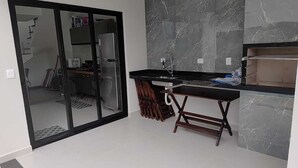 A modern kitchen with a black countertop, a sink, and a marble backsplash. - Refuge 3 Indaiá Beach Bertioga 150 meters from the sea (Bertioga)