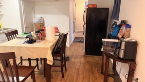 Uma cozinha com mesa de jantar, cadeiras, geladeira e cafeteira.