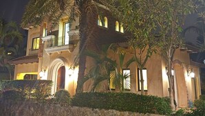 A two-story building with a stone facade, arched windows, and a balcony. - Chivani modern private pool villa with garden in Na Jomtien Pattaya (Tambon Na Chom Thian)