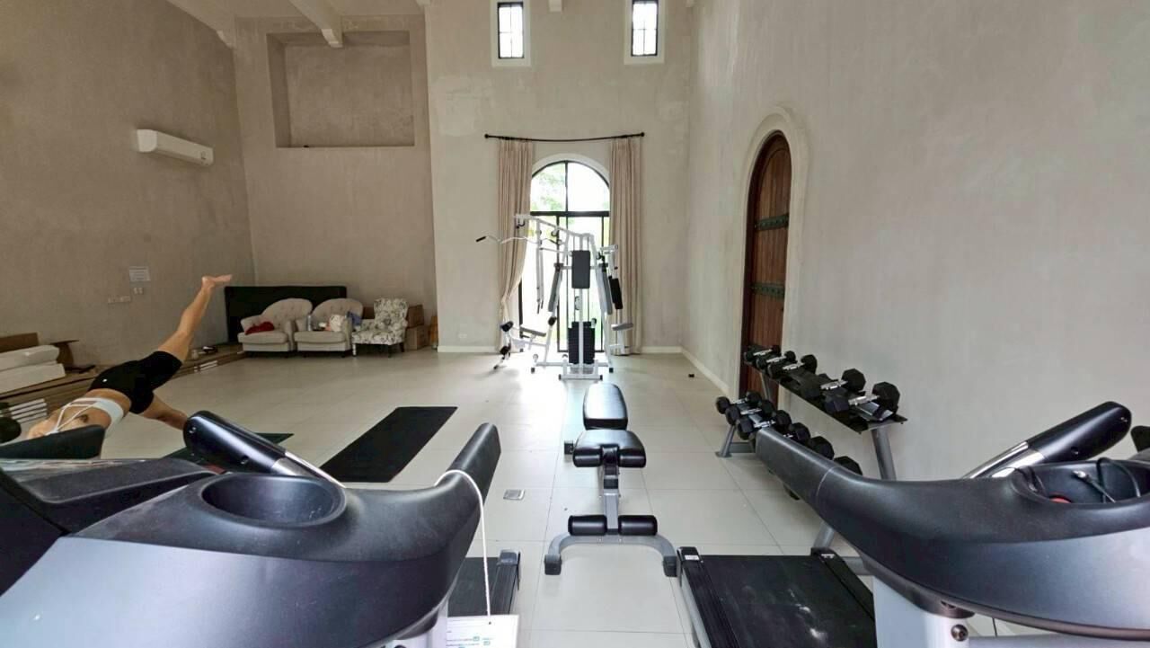 Un gimnasio con cintas de correr, una prensa de pesas y un soporte para pesas.