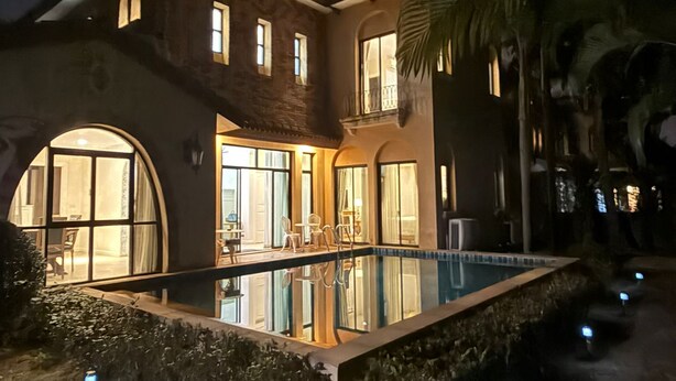A two-story house with a swimming pool, large windows, and a well-lit entrance. - Chivani modern private pool villa with garden in Na Jomtien Pattaya (Tambon Na Chom Thian)