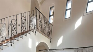 A spacious living room with a fireplace, leather sofas, a coffee table, and a staircase with ornate railings. - Chivani modern private pool villa with garden in Na Jomtien Pattaya (Tambon Na Chom Thian)