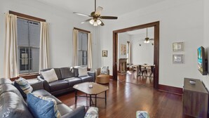 Un salón amplio con un sofá de cuero oscuro, una mesa de centro y un ventanal con cortinas.