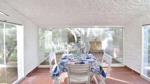A room with a table and chairs, large windows, and a view of trees. - Detached cottage with a/c and two bathrooms (Aglientu)