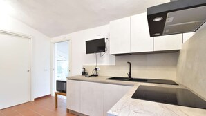 A modern kitchen with white cabinets, a black countertop, and a built-in stove. - Detached cottage with a/c and two bathrooms (Aglientu)