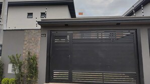 Et moderne hus med stor garageport, et lille vindue og et skilt med nummer 44 på væggen.
