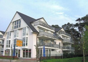 Ein mehrgeschossiges Wohngebäude mit Balkonen, großen Fenstern und einem sichtbaren Eingangsbereich im Erdgeschoss.