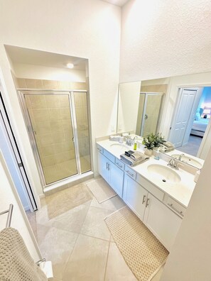 Une salle de bain moderne dotée d’une douche à parois de verre, de deux vasques et d’un grand miroir.