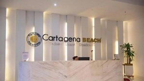 Un mostrador de recepción con encimera de mármol, un logotipo y el texto "Cartagena Beach Exclusive Resort Residences".