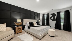 Een moderne slaapkamer met een groot bed, een nachtkastje, een slaapbank en een zacht vloerkleed.