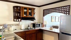 A compact kitchen with a sink, microwave, and wooden cabinets. - With preferential price for monkey tours (Quepos)