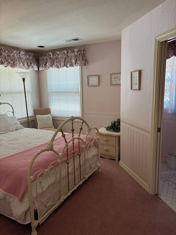 A bedroom with a bed, a nightstand, a dresser, and a window with blinds.