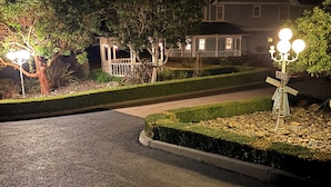 A well-lit residential driveway at night with a house in the background, surrounded by landscaped gardens and trees. - Beautiful 5-bedroom house in rural San Luis Obispo near Avila and Pismo Beach (San Luis Obispo)