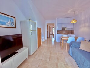 A modern apartment with a living area, a dining space, and a kitchenette. - Sa Caleta Apartment with swimming pool next to the beach (Cala En Blanes)