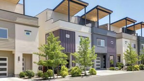 A modern residential building with multiple units, each featuring a garage, a balcony, and a flat roof design. - Spacious 2-bedroom with Loft townhome in charming Reno with all the amenities (Reno)