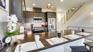 A modern kitchen with dark cabinetry, stainless steel appliances, and a central island with a marble countertop. - Spacious 2-bedroom with Loft townhome in charming Reno with all the amenities (Reno)