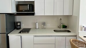 A modern kitchen with white cabinets, a black microwave, a coffee maker, a toaster, and a sink. - 🌴 Escape to Paradise! Live the Cartagena Beach Resort Experience (Cartagena de Indias)