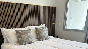 A neatly made bed with white bedding and a folded towel, a wooden slatted headboard, and a window with a view. - 🌴 Escape to Paradise! Live the Cartagena Beach Resort Experience (Cartagena de Indias)