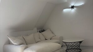 Una sala moderna con un sofá blanco, una mesita redonda y un ventilador de techo.