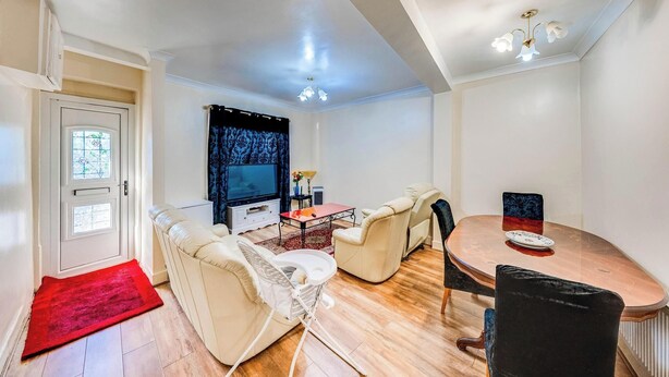 Uma sala de estar com sofá, cadeiras, mesa de centro, televisão e mesa de jantar.