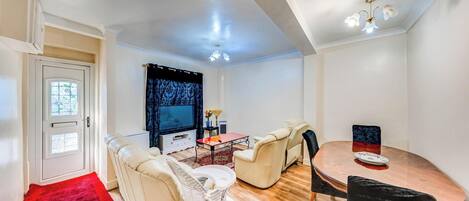 A living room with a sofa, chairs, a coffee table, a TV, and a dining table.