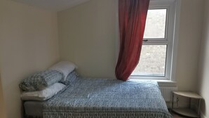 Quarto com cama, janela e radiador.