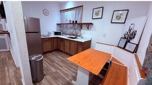 Une cuisine compacte avec des meubles en bois, un réfrigérateur en acier inoxydable, un évier et une table en bois.