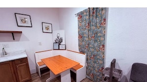 Une cuisine compacte avec une table et des bancs en bois, un petit meuble et un élément décoratif mural.