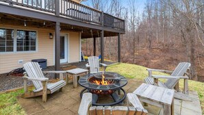 An outdoor patio with a fire pit, wooden chairs, and a covered deck area. - Stunning Mountain Retreat! Packed with Fun! Air Hockey Table! - Two Sisters Chalet (Fancy Gap)