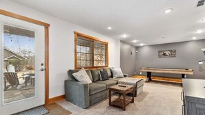 A living room with a grey sofa, a wooden coffee table, and a bench. - Stunning Mountain Retreat! Packed with Fun! Air Hockey Table! - Two Sisters Chalet (Fancy Gap)
