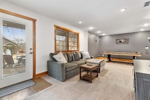 A living room with a grey sofa, a wooden coffee table, and a bench. - Stunning Mountain Retreat! Packed with Fun! Air Hockey Table! - Two Sisters Chalet (Fancy Gap)