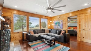A cozy living room with a sectional sofa, a coffee table, and a ceiling fan. - Stunning Mountain Retreat! Packed with Fun! Air Hockey Table! - Two Sisters Chalet (Fancy Gap)