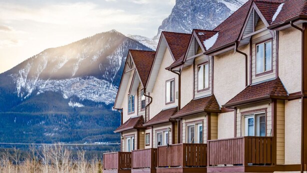 Une rangée de bâtiments de style chalet, avec une chaîne de montagnes en arrière-plan.