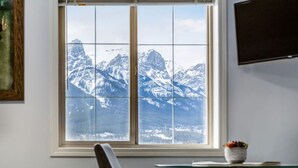 Une pièce dotée d’une grande fenêtre donnant sur des montagnes enneigées.