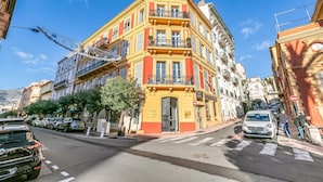 Ein mehrstöckiges Gebäude mit gelber Fassade, Balkonen und Blick auf die Straße.