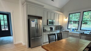 Una cocina moderna con armarios blancos, electrodomésticos de acero inoxidable y una mesa de comedor de madera.